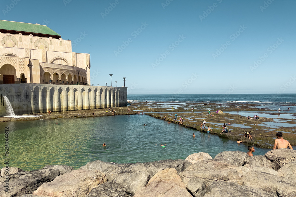 People swimming in the ocean next to Hassan II mosque in Casablanca