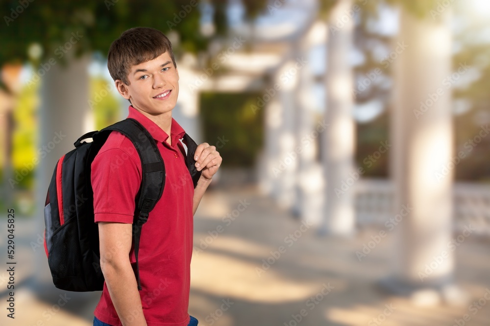 Naklejka premium Happy young student standing with a backpack and posing