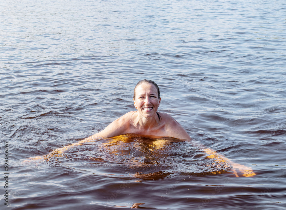 Cheerful young woman bathing in the lake