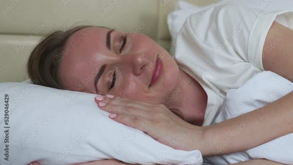 Young woman with closed eyes lies on comfortable bed hugging soft pillow. Happy female guest enjoys sleeping in morning in hotel room closeup Young woman with closed eyes lies on comfortable bed hugging soft pillow. Happy female guest enjoys sleeping in morning in hotel room closeup