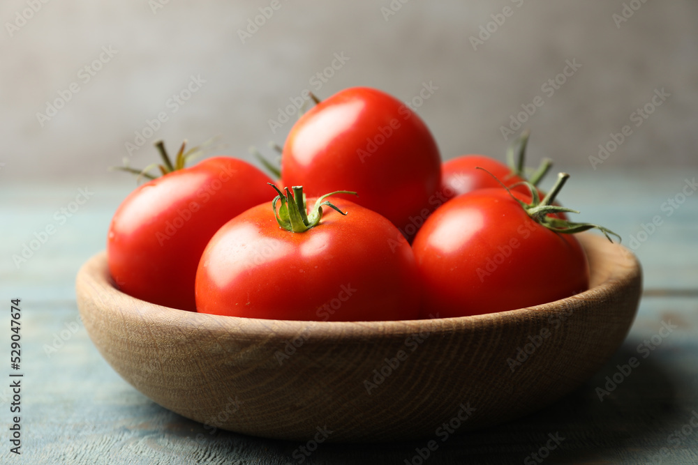 Ripe tomatoes in bowl on blue wooden table, closeup Ripe tomatoes in bowl on blue wooden table, closeup