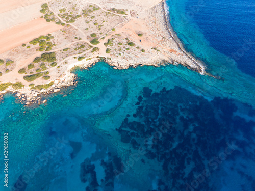 Marine background of the Mediterranean sea surface. Drone view. Stone cape of the island. Exotic water landscape. Lonely white lighthouse. Natural tropical paradise. Camping in Cyprus.