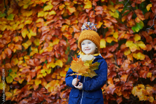 Adorable preschooler girl enjoying nice and sunny autumn day outdoors