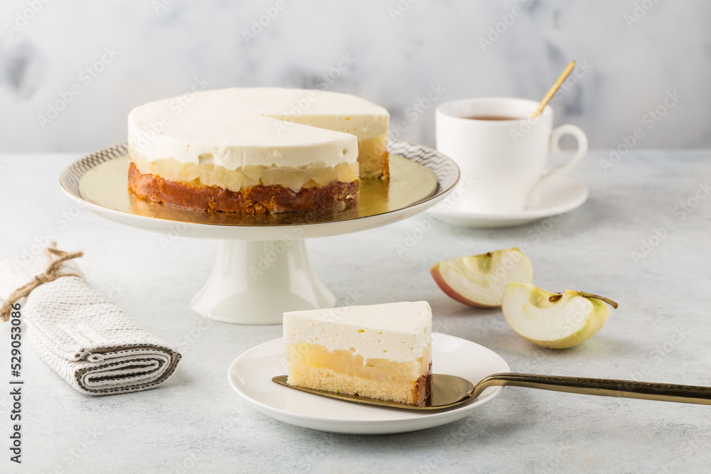 Apple cheesecake on cake stand and cup of tea. White background.