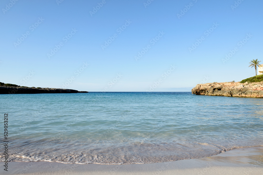 Sea shore at a tropical beach with clear ocean water and sand