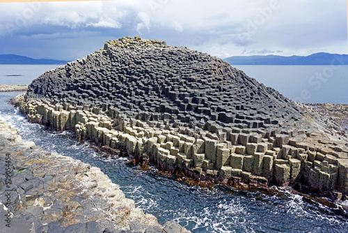 The islet of Am Buachaille with its unique hexagonal basalt columns formed 55 million years ago by the cooling core of a volcano, lies on the east side of the Isle of Staffa in the Scottish Hebrides. photo