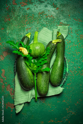 Assortment of organic courgettes and zucchinis on green background