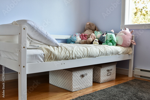 Modern child's room with favourite stuffies on bed and simple storage solution ideas for toys under the bed