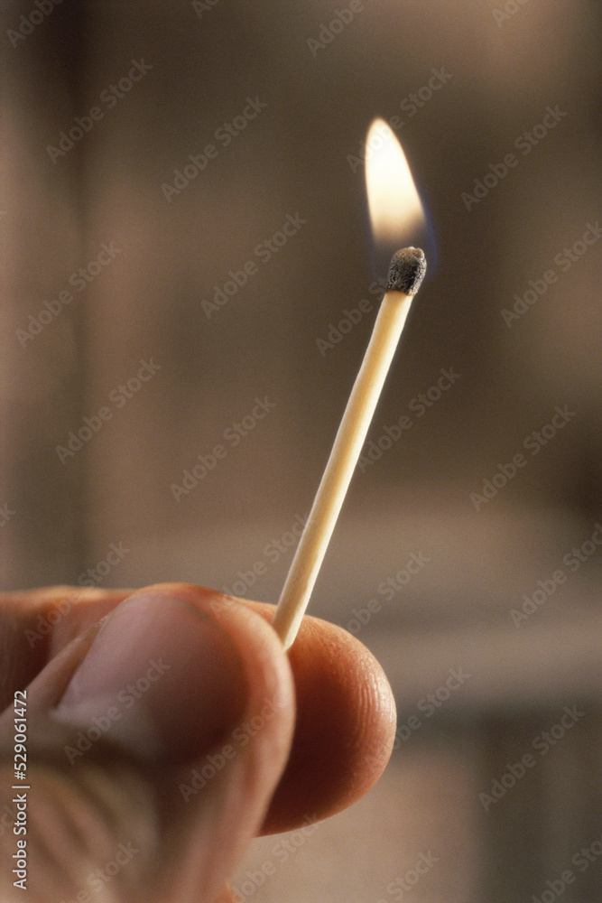 Person holding a burning matchstick