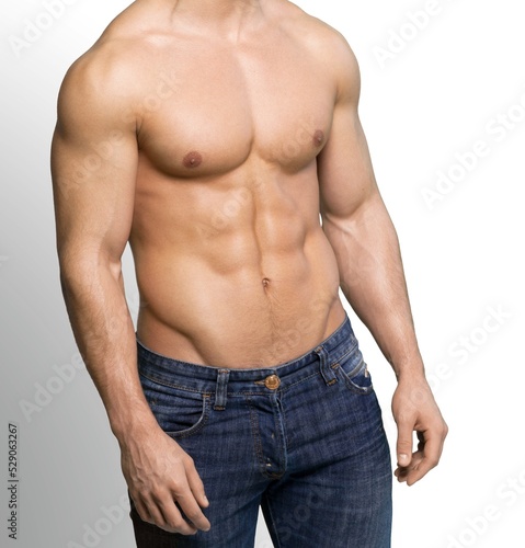 Handsome muscular young man posing against a grey background.