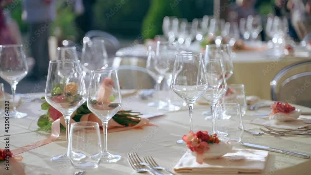 Elegant round table setting in luxury restaurant in the open air, round tables with crystal goblets, exclusive silverware, trendy placeholders and charming flowers bouquets in the middle of the table Elegant round table setting in luxury restaurant in the open air, round tables with crystal goblets, exclusive silverware, trendy placeholders and charming flowers bouquets in the middle of the table