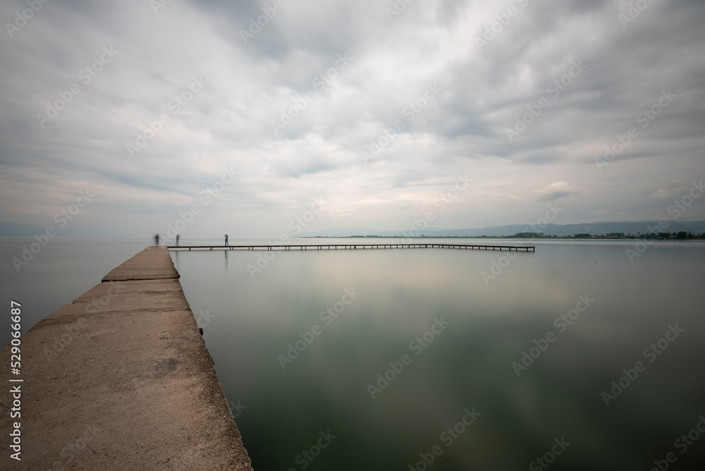 Person at pier, iznik lake and pier on shore with a person and clouds boats and silhouettes