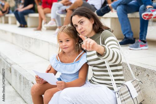 Woman and daughter sitting on stone stairs in Barcelona city center