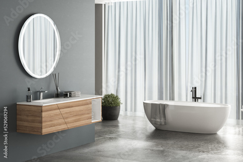 Leinwand Poster Modern bathroom interior with blue background, concrete flooring, white bathtub, shower and sink, side view