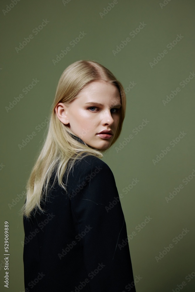 Cool banner for brands. An attractive cool professional model poses in a half-turn and looks at the camera on a green olive background in the studio Cool banner for brands. An attractive cool professional model poses in a half-turn and looks at the camera on a green olive background in the studio