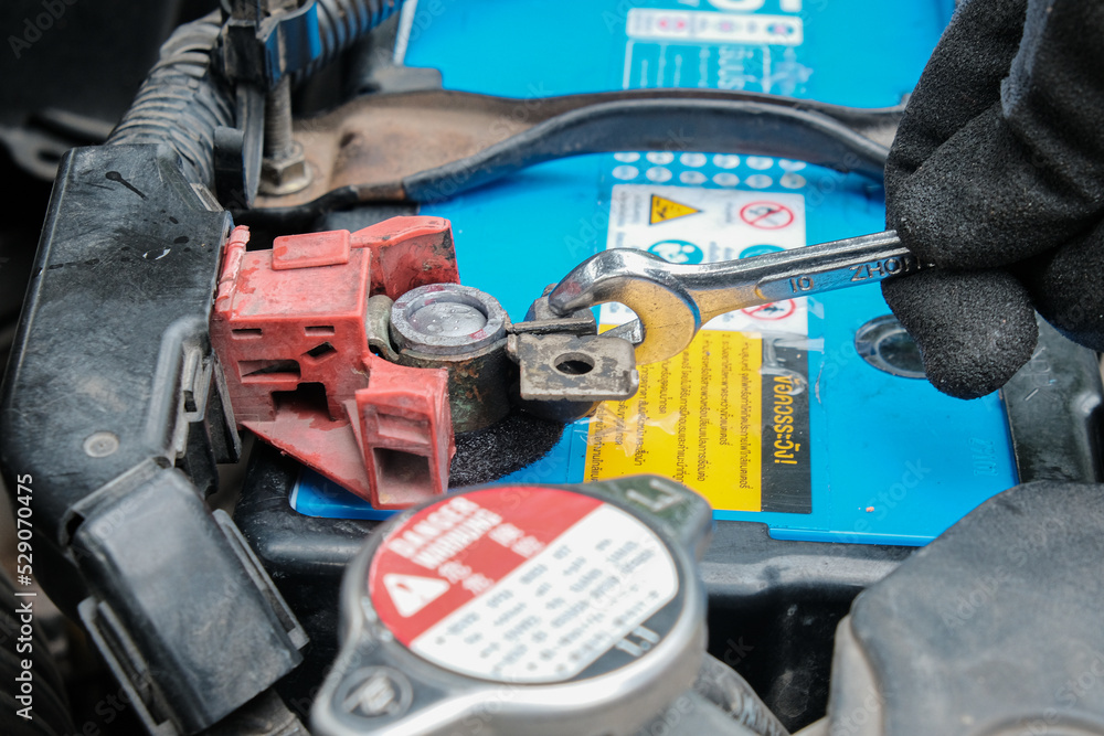 Mechanical man hand checking car batterry with multimeter Mechanical man hand checking car batterry with multimeter