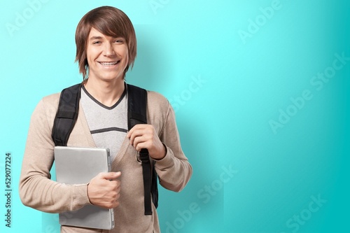 Male student with backpack on light background