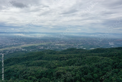 Top view of mountain in Chiang Mai City, Thailand. White cloud and dust is above of the mountain while cities can be seen far away.