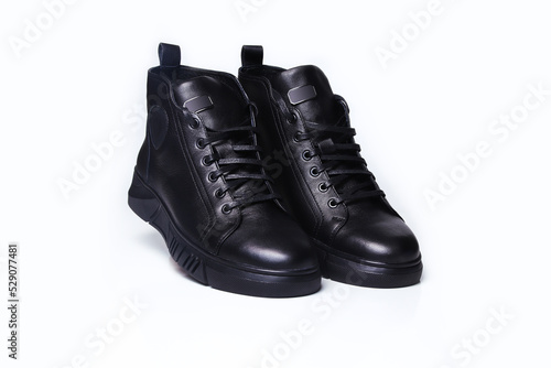 Defocus black leather male shoes, white background. Men’s ankle boot leather isolated on white background, closed up. Winter boots. Out of focus