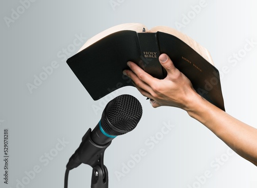 Pastor with a Bible in hand during a sermon. The preacher delivers a speech photo