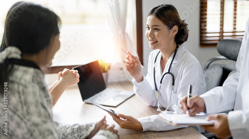 Doctor and patient are discussing at clinic. Young asian female doctor give advice on treatment with her patient. photo