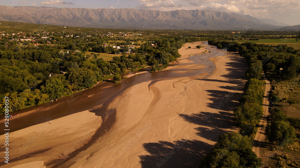 Aerial view of sandy parched river during holidays in Cordoba,Argentina - Idyllic landscape fields and mountain range in backdrop
