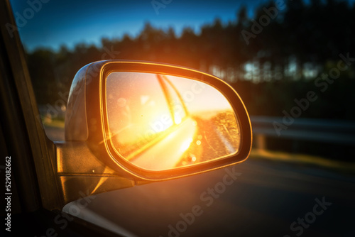 Road sunset car mirror. Summer sun, highway car road reflection in mirror. Vacation trip concept. © Maksym
