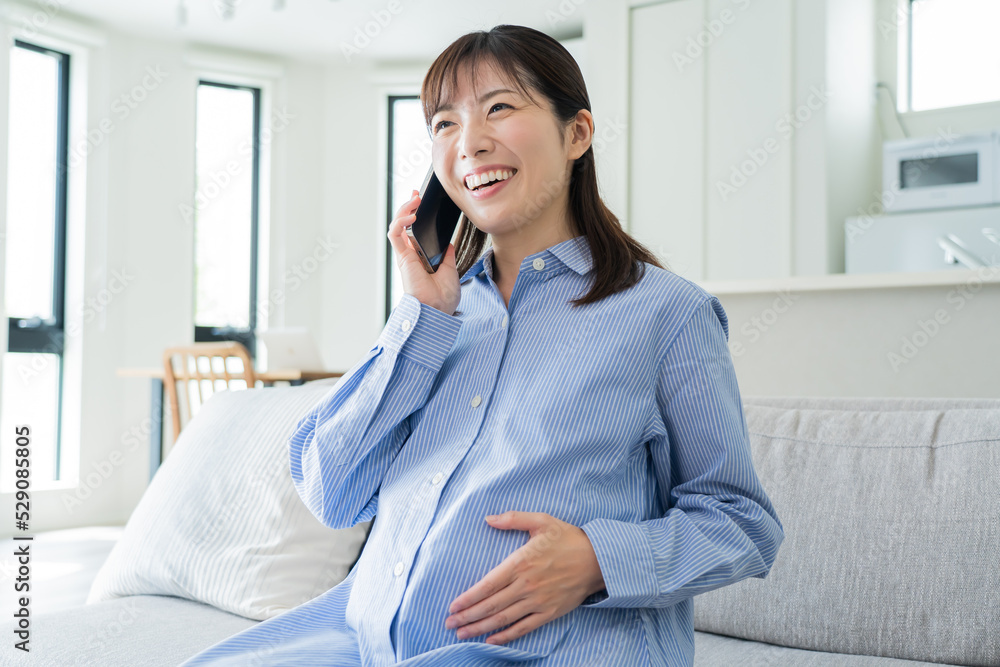 Fototapeta premium 自宅で電話をかける日本人妊婦