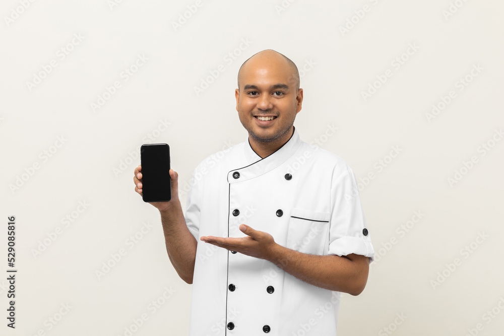 Young asian male chef showing empty screen cellphone to choose various delicious dish menu good taste for customer order. Online smartphone delivery food buying variety of dish Young asian male chef showing empty screen cellphone to choose various delicious dish menu good taste for customer order. Online smartphone delivery food buying variety of dish