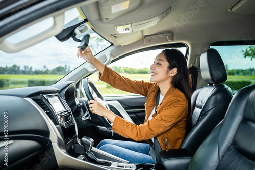 Young beautiful asian women getting new car. she very happy and excited hand adjust the rearview mirror before driving car safety travel. © Chanakon