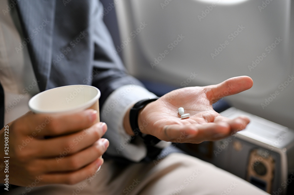 close-up, A male passenger holding a cup of water and an airsick motion sickness pills.