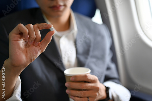 Foto A male passenger holding a cup of water and an airsick motion sickness pills