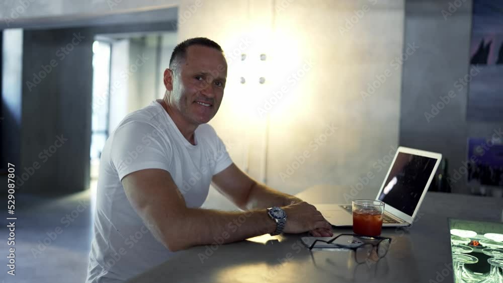 Smiling businessman working on laptop computer at home office. Male professional typing on laptop keyboard at office workplace. Portrait of positive business man looking at laptop screen indoors Smiling businessman working on laptop computer at home office. Male professional typing on laptop keyboard at office workplace. Portrait of positive business man looking at laptop screen indoors