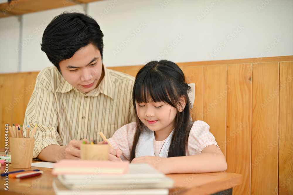 Lovely cute young Asian girl doing homework, having an art class with her private tutor. Lovely cute young Asian girl doing homework, having an art class with her private tutor.