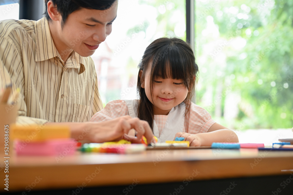 Happy Asian dad and daughter playing and moulding play dough together. Happy Asian dad and daughter playing and moulding play dough together.