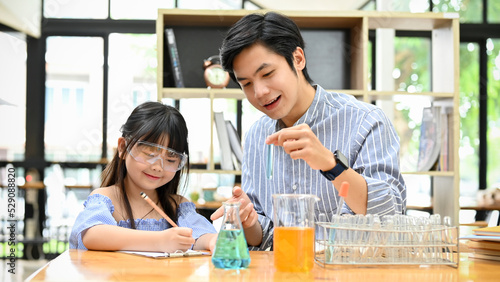 A cute little Asian girl studying science at home with her private tutor.