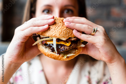 Fast food burger eat. Pretty Young Happy Woman Eating Tasty Hamburger. Junk Food Concept.