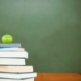 Green apple on pile of books in classroom