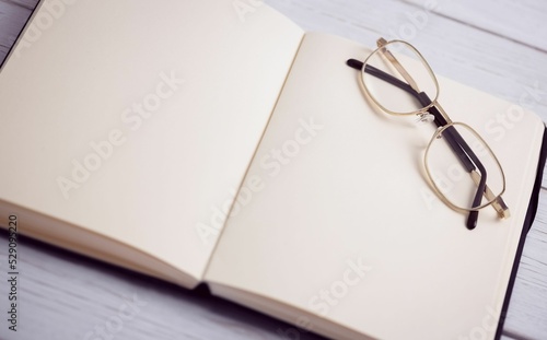 Book with eyeglasses on wooden table