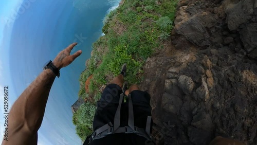 POV shot of a man carefully hiking on a narrow and dangerous path on the side of Quebrada do Negro in Madeira.