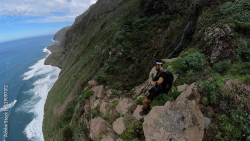 A young and strong man is hiking down the edge of Quebrada do Negro in Madeira.