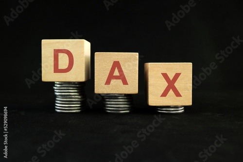 German DAX performance stock market index crash and bear market due to financial crisis and recession in Germany. Wooden blocks in with coins in dark black background. photo
