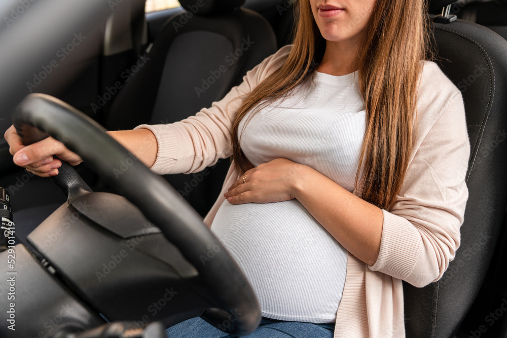 Woman driving car. Beautiful smiling pregnant woman driving car. Safety pregnancy young mother drive concept.