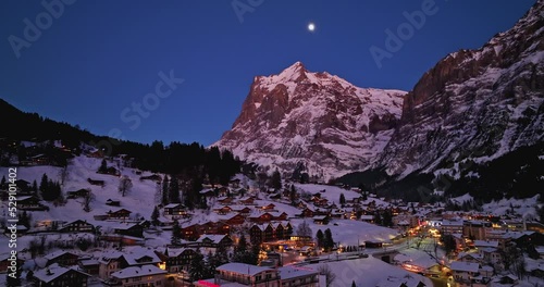 Panorama aerial Drone shot of Cottages chalets in Murren village at snowy winter night. Mürren traditional Walser mountain village in the Bernese Highlands of Switzerland. popular tourist spots.