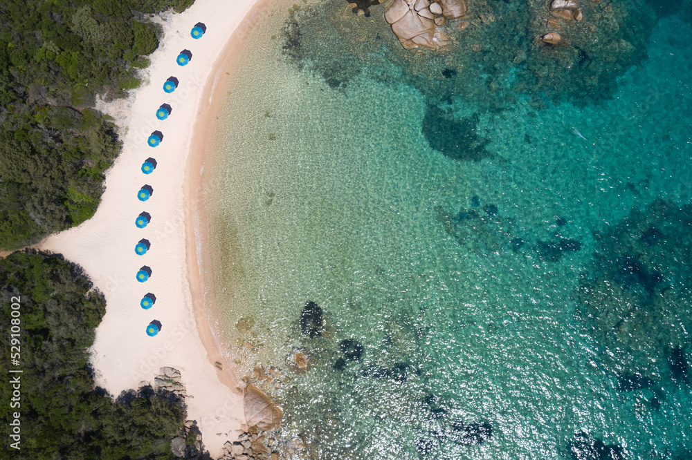White beaches of Sardinia aerial view. Blue umbrellas along the coastline on the beach top view. Transparent beaches of sardinia aerial view.