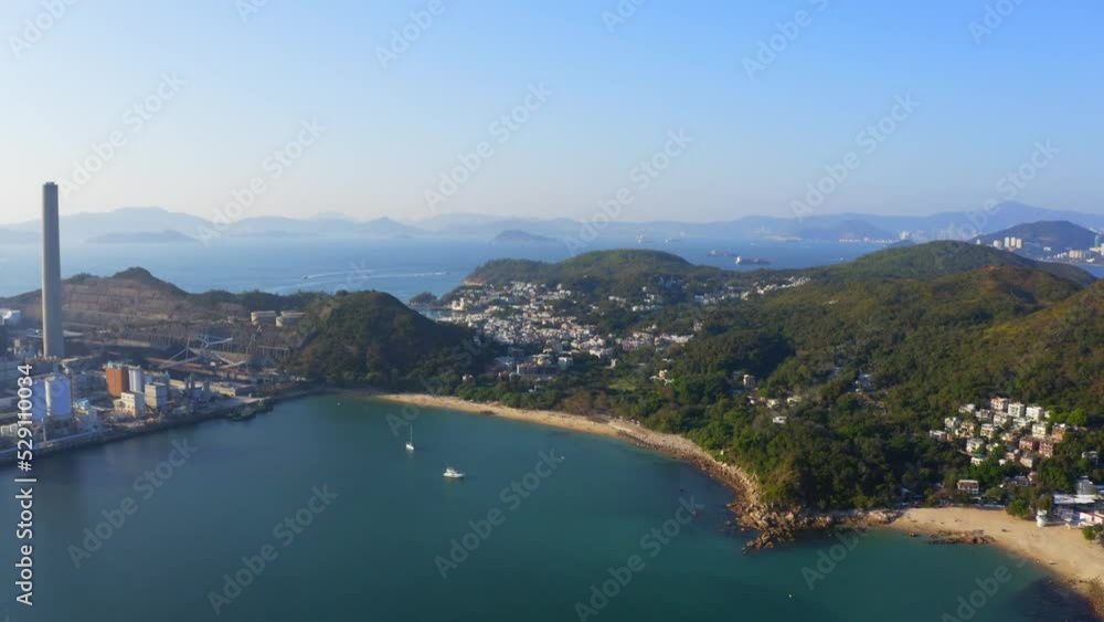 Drone shot of a big coastal coal-fired power plant on an island next to a village with a beach during a beautiful sunny day. The camera traveling to the right. Drone shot of a big coastal coal-fired power plant on an island next to a village with a beach during a beautiful sunny day. The camera traveling to the right.