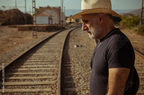 Adult man in jeans carrying bag railway track