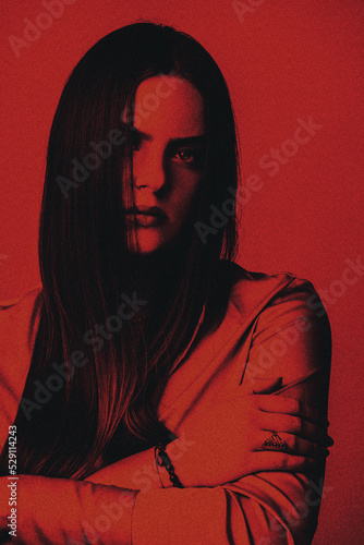 Fashion, style, make-up concept. Beautiful woman with long dark hair studio portrait. Face partly covered with hair. Red filter with grain applied to make horror and mystique atmosphere