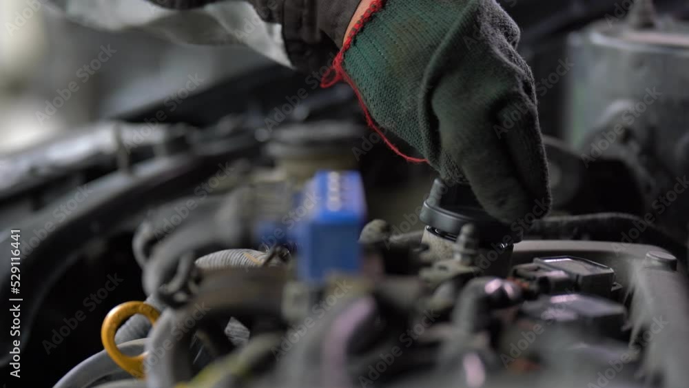Inspection of the engine and checking the motor oil level, The car is checking the engine oil level, and the mechanic is pouring oil into the engine. Inspection of the engine and checking the motor oil level, The car is checking the engine oil level, and the mechanic is pouring oil into the engine.