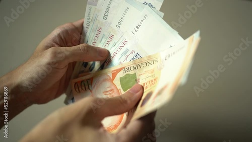 Manually counting Singapore dollar banknote with hand photo